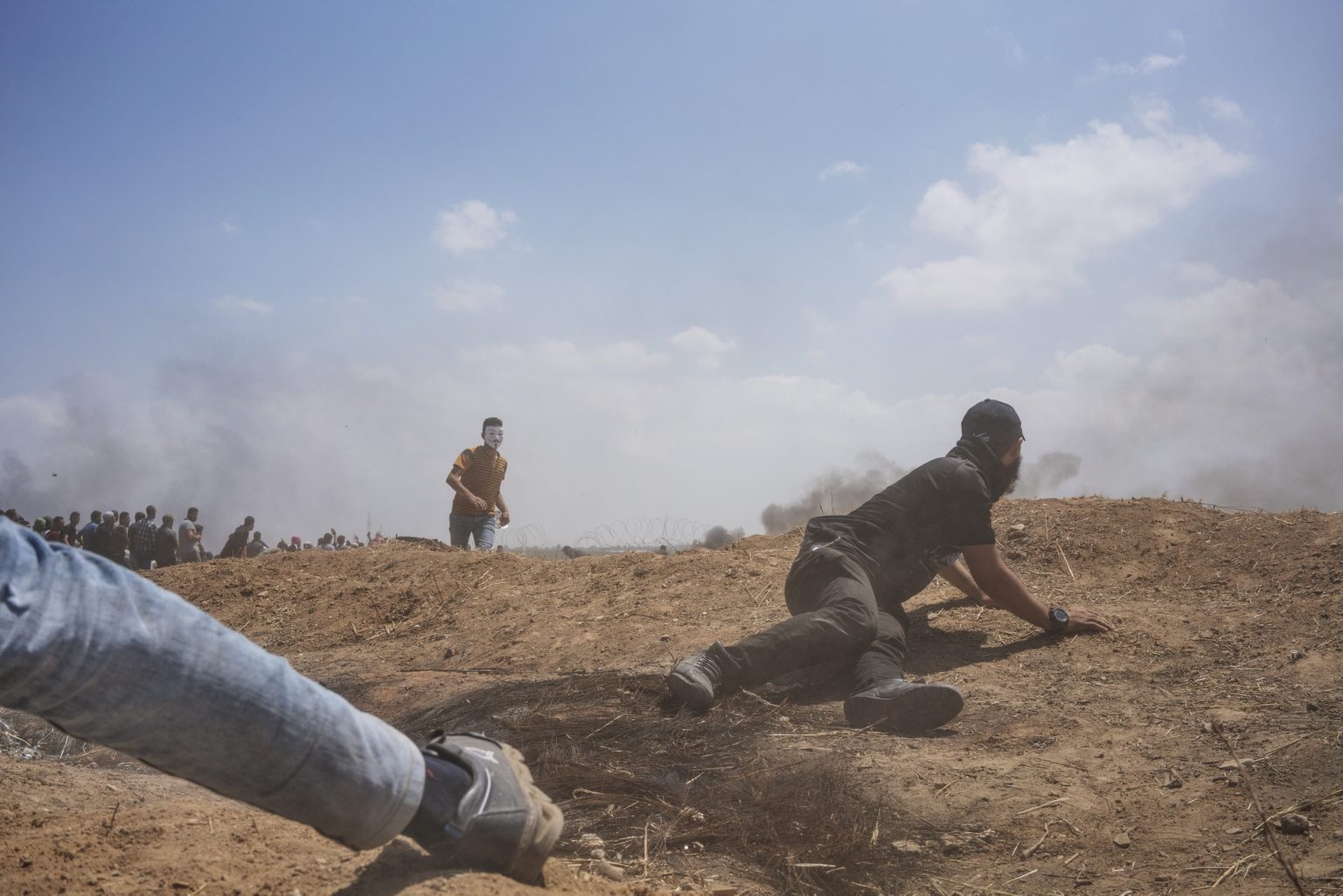 Gaza Strip, May 2018 - A man hides behind an embankment during the protest along the Gaza-Israel border. ><
Striscia di Gaza, maggio 2018 - Un uomo si ripara durante le proteste lungo il confine tra Gaza e Israele.