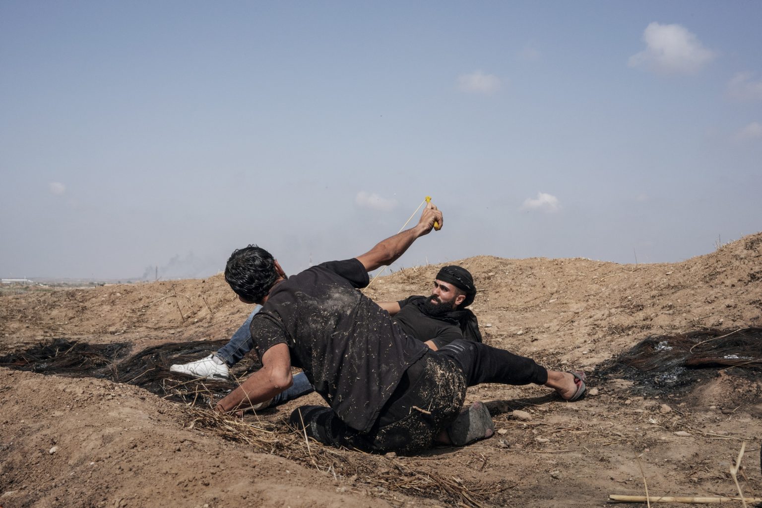Gaza Strip, May 2018 - Palestinian protesters use slingshots to throw stones near the border fence with Israel during the demonstration. ><
Striscia di Gaza, maggio 2018 - Dimostranti palestinesi usano delle fionde per lanciare sassi verso il confine israeliano.
