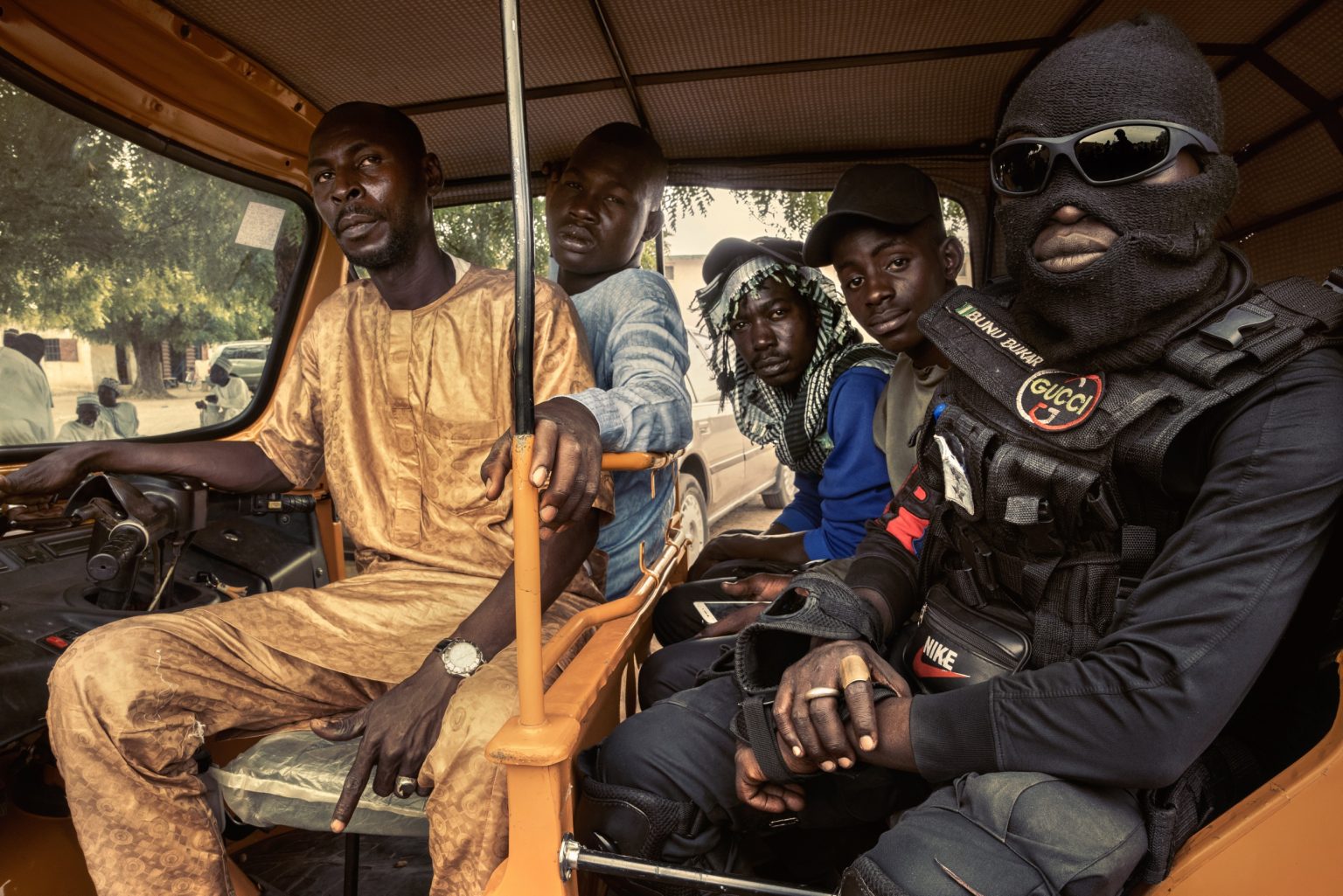 Maiduguri, Nigeria, Africa, May 2021 - A group of the Civilian Joint Task Force (CJTF) pose for a picture in a rickshaw.  The Civilian Joint Task Force (CJTF) is a group of militants that was formed in Maiduguri, Borno State, Nigeria to help oust Boko Haram Islamist fighters from their city. The vigilante group numbers over 26,000 in the northeastern Borno and Yobe States. In June 2013, the civilian JTF emerged and volunteered to assist the Special and Joint Task Force with the counter-terrorism campaign. The civilian JTF is made up of young and old civilians armed with mundane weapons such as bows and arrows, swords, clubs and daggers that operate under the supervision of civilian JTF sector commanders. The civilian JTF began as a community effort and later as a joint effort with the security forces to help fight Boko Haram. Maiduguri city has gone back to normalcy with the aid of the civilian JTF.  ><
Maiduguri, Nigeria, Africa, maggio 2021 -  Un gruppo del Civilian Joint Task Force' (CJTF) -posano per una foto in un rickshaw. Il CJTF è un gruppo di militanti che si è formato a Maiduguri, nello stato di Borno, in Nigeria, per aiutare a cacciare i combattenti islamisti di Boko Haram dalla città. Il gruppo di vigilanti conta oltre 26.000 membri negli Stati nord-orientali di Borno e Yobe. La JTF è nata nel giugno 2013 su base volontaria di civili che si sono offerti di affiancare la task force speciale e congiunta nella campagna antiterrorismo. La JTF è composta da civili giovani e anziani armati di armi come archi e frecce, spade, mazze e pugnali. La città di Maiduguri è tornata ad una pseudo normalità grazie al loro impegno.