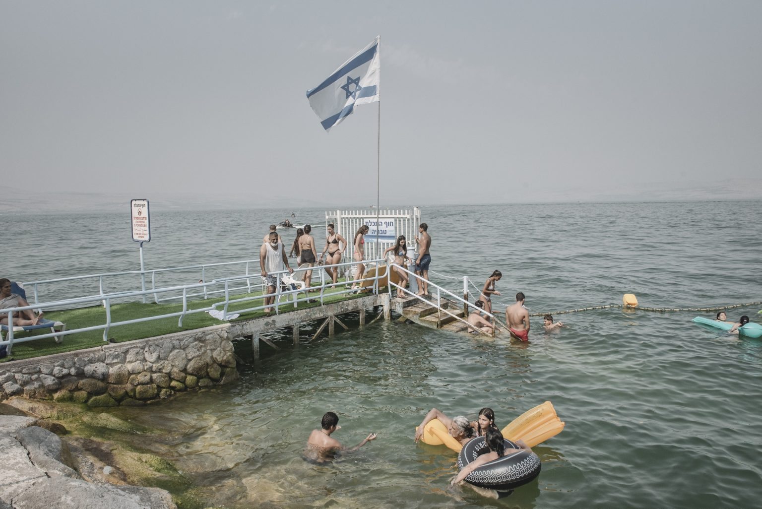 16.15604521 Tourists in the Sea of Galilee in Tiberias, Israel, Aug. 27, 2021.  Two journalists for The New York Times drove the length of Israel to discover what it means to be Israeli today. They met a kaleidoscope of people, searching for belonging but far apart on how to find it. (Laetitia Vancon/The New York Times)     <span style="color: #ff0000">*** SPECIAL   FEE   APPLIES ***</span> *** Local Caption *** 16.15604521