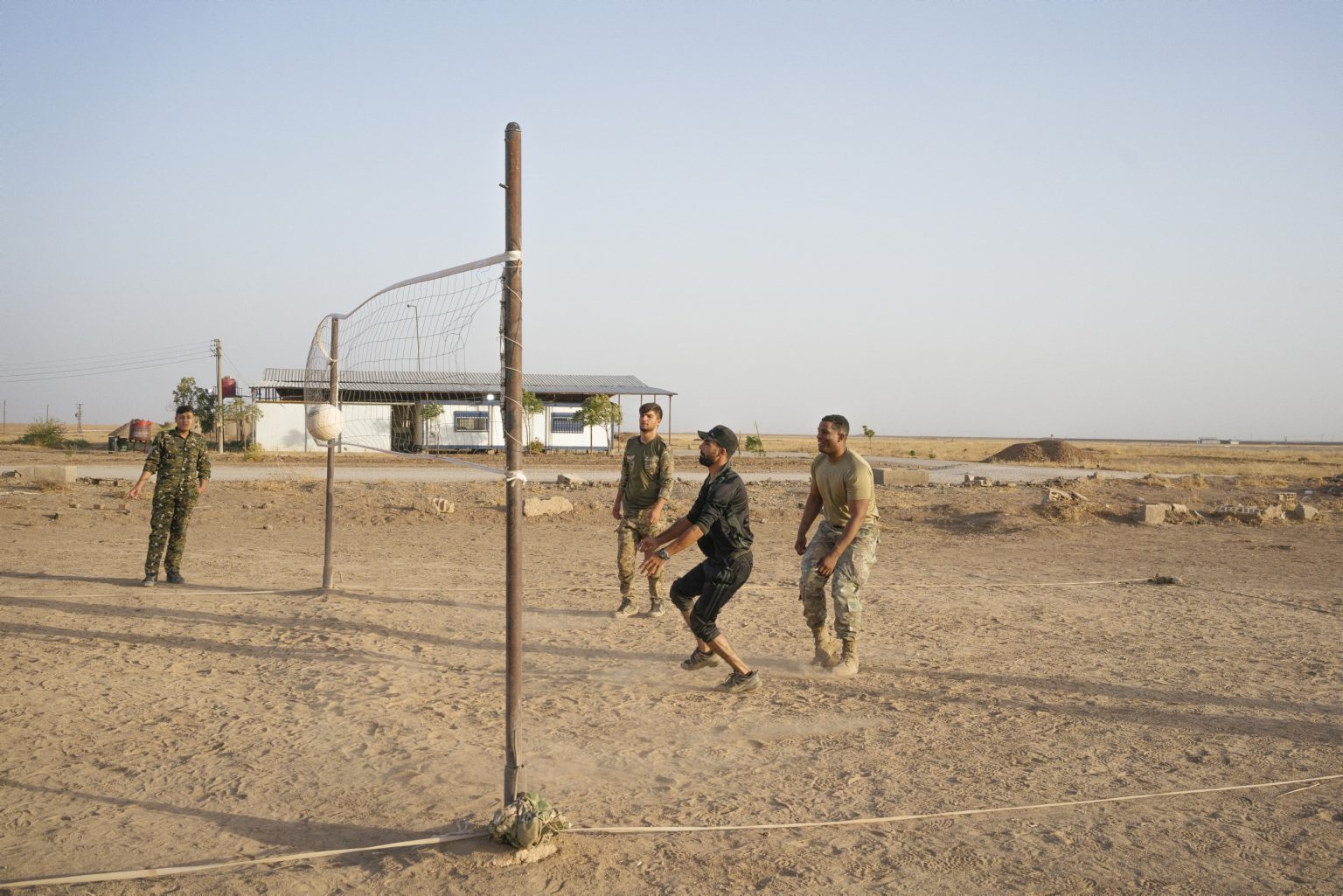 SYRIA. August 24, 2021 - Members of the Kurdish-led Syrian Democratic Forces (SDF), and a U.S. Army soldier, play volleyball inside a remote U.S. Army combat outpost in northeastern Syria, known as RLZ.

SIRIA. 24 agosto 2021 - Membri delle Forze Democratiche Siriane (SDF) e soldati dell'esercito americano, giocano a pallavolo all'interno di un avamposto dell'esercito americano nel nord-est della Siria, noto come RLZ.