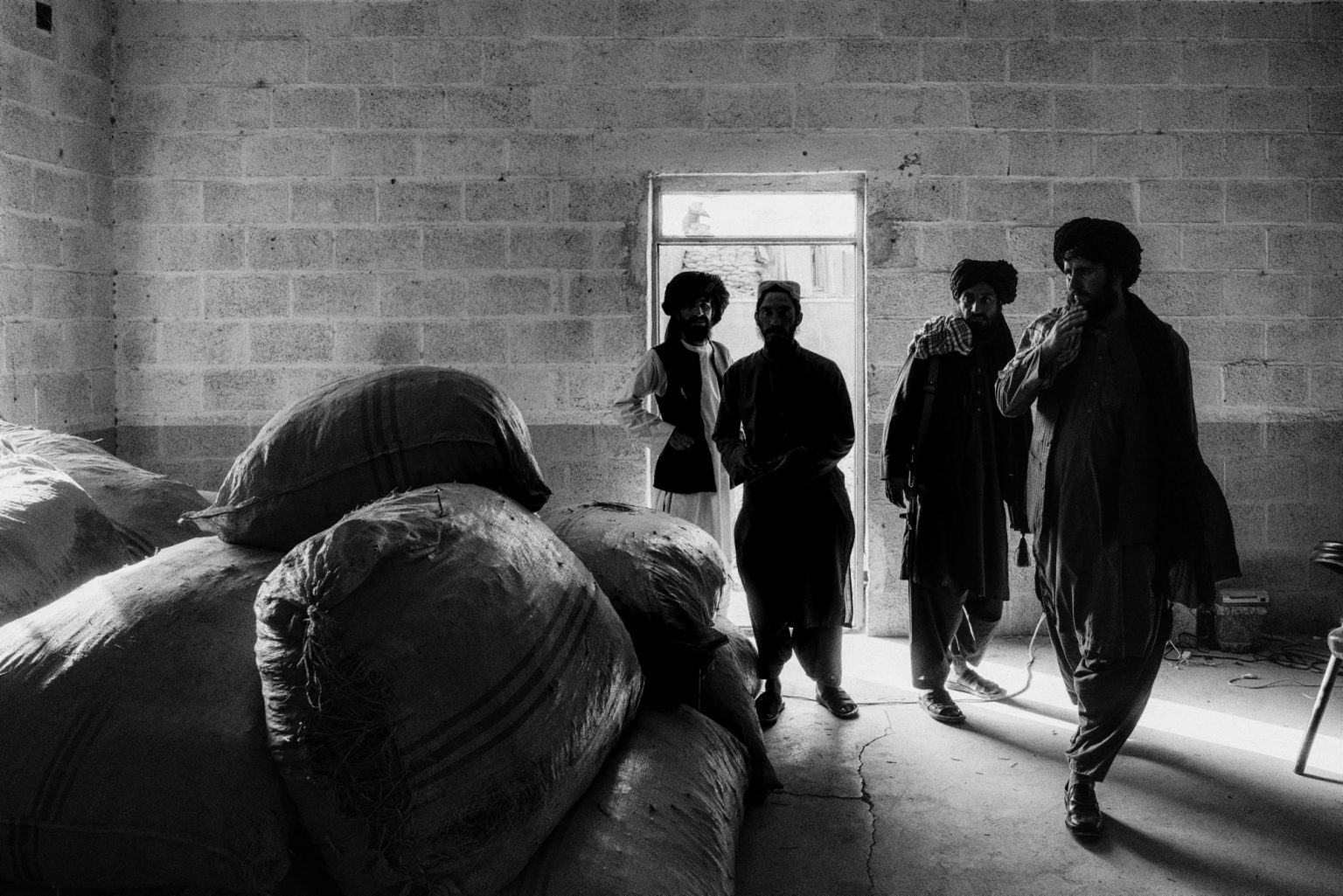 FARAH PROVINCE, AFGHANISTAN - MARCH 18, 2022:
Taliban fighters enter a warehouse filled with sacks of ephedra plants that they have confiscated. The plan is used to produce methamphetamine.
(Photo by Lorenzo Tugnoli/ Washington Post/ Contrasto)
