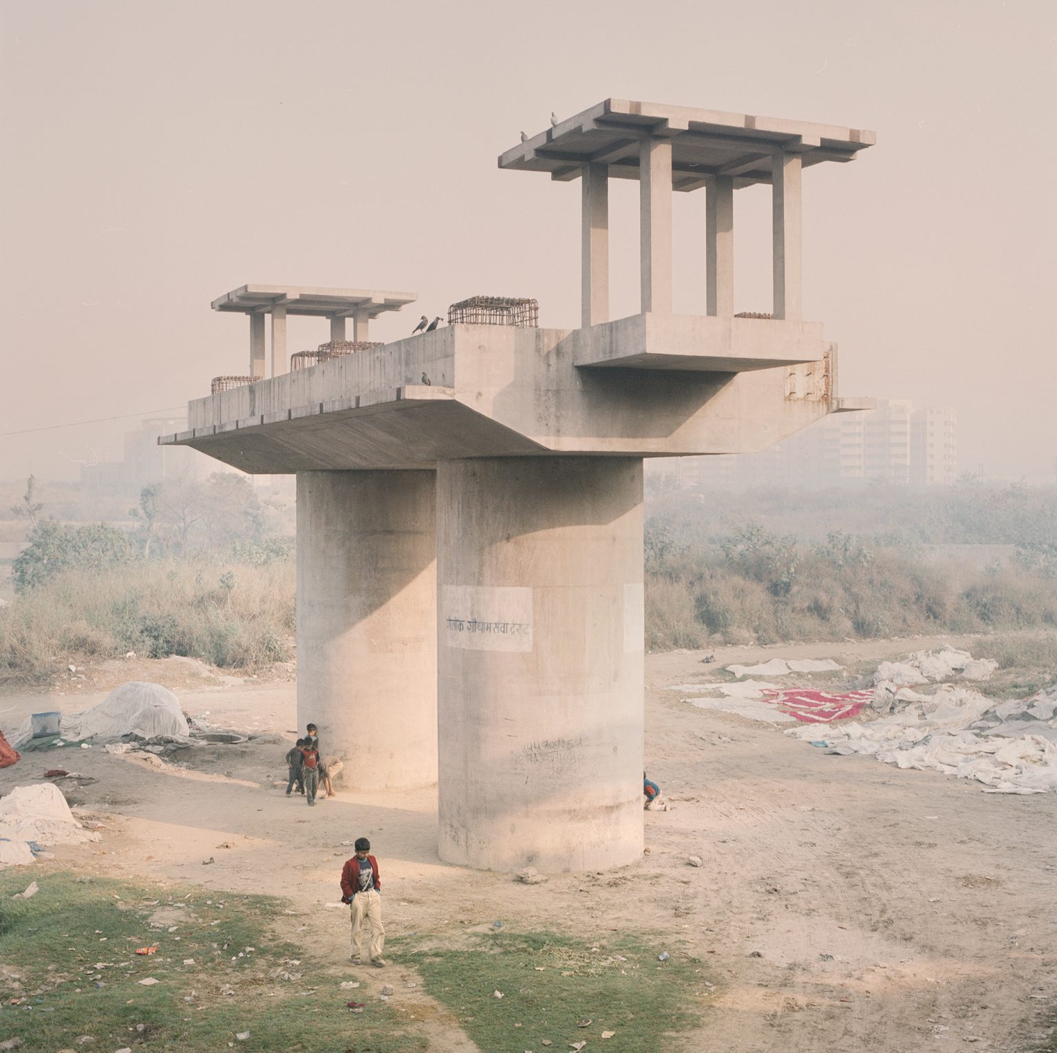 An outdoor makshift laundry for hotels along the Yamuna river in Delhi, near a pillar for the constuction of a new bridge.