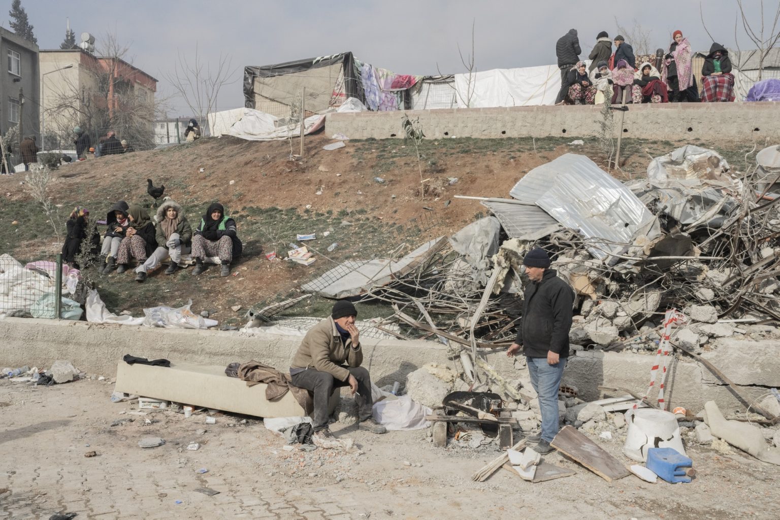 Kahramanmaras¸, Turkey, February 2023 - The aftermath of the earthquake that hit southern Turkey and northern Syria.     Civilians sit in front of a damaged area of the city.><
Kahramanmaras¸, Turchia, febbraio 2023  Le conseguenze del terremoto che ha colpito la Turchia del Sud e la Siria del nord.