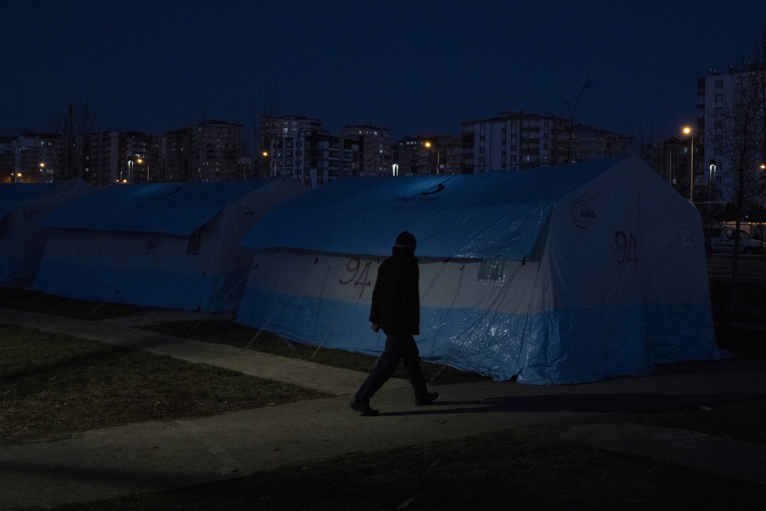 Diyarbakir, Turkey, February 2023 - The aftermath of the earthquake that hit southern Turkey and northern Syria. A man walks inside a tent camp set up in the city of Diyarbakir.><
Diyarbakir, Turchia, febbraio 2023  Le conseguenze del terremoto che ha colpito la Turchia del Sud e la Siria del nord.