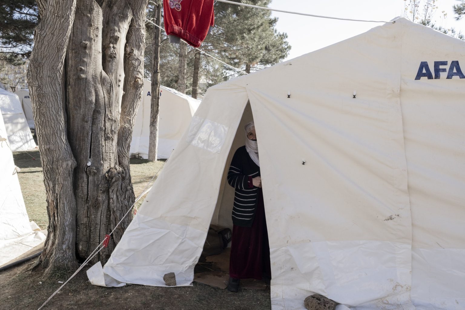 Diyarbakir, Turkey, February 2023 - The aftermath of the earthquake that hit southern Turkey and northern Syria. A woman stand inside her tent in a tent camp in the city of Diyarbakir.><
Diyarbakir, Turchia, febbraio 2023  Le conseguenze del terremoto che ha colpito la Turchia del Sud e la Siria del nord.